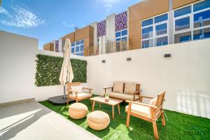 un patio con sillas y una mesa frente a un edificio en Peaceful 3BR Townhouse at DAMAC Hills 2, Dubailand by Deluxe Holiday Homes, en Dubái