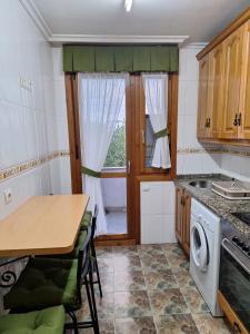 a kitchen with a wooden table and a table and a stove at Apartamento Cueto in Soto del Barco