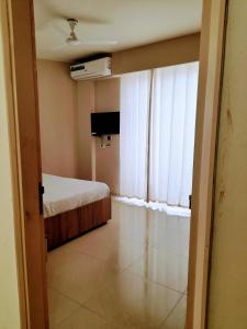 a room with a bed and a television and a window at Sridham Holiday Vrindavan in Vrindāvan +23 photos