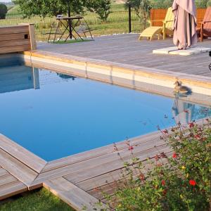 a swimming pool with a wooden deck and a duck in the water at La Chartreuse d'Ertan "Les maîtres" 4 étoiles in Saint-Christophe-des-Bardes