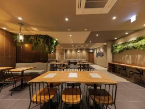 ein Restaurant mit Tischen und Stühlen und Pflanzen an der Wand in der Unterkunft Super Hotel Sapporo Kitagojo Dori in Sapporo + 49 Fotos