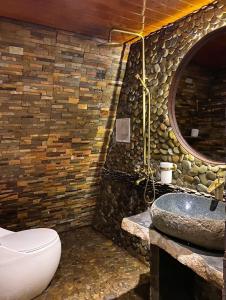 a bathroom with a stone wall with a toilet and a sink at Nhà Yên 's 2 Bedrooms Lake Resort Hotel Homestay in Pleiku