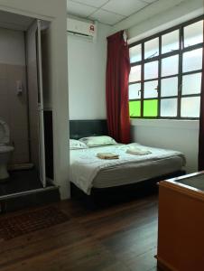 a bedroom with a bed and a window and a toilet at Meera Heritage Motel in George Town
