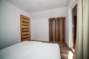 a bedroom with a white bed and a wooden door at Comfortable two story holiday houses Jaros awiec in Jarosławiec