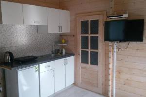 a kitchen with white cabinets and a flat screen tv at Cottage for 4 people Ustronie Morskie in Ustronie Morskie