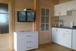 a kitchen with white cabinets and a tv on a wall at Cottage for 4 people Ustronie Morskie in Ustronie Morskie