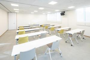 uma sala de aula vazia com mesas brancas e cadeiras amarelas em Teshima ESPOIR PARK em Ieura