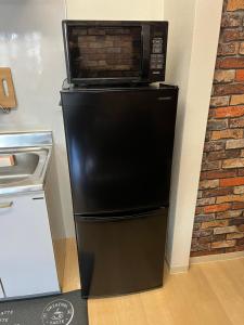 a black refrigerator with a microwave on top of it at 小団体大関係 in Toda
