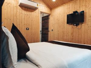a bedroom with a bed and a flat screen tv at Farm Stay Resort - Shamirpet, Hyderabad in Hyderabad