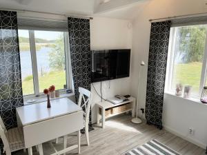 Cozy cottage located on a nice sea plot on Boholmarna outside Kalmar في كالمار: غرفة بها مكتب وتلفزيون ونوافذ