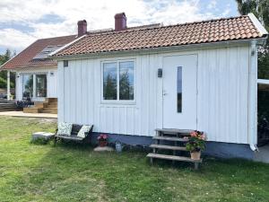 uma pequena casa branca com um banco e um alpendre em Cozy cottage located on a nice sea plot on Boholmarna outside Kalmar em Kalmar