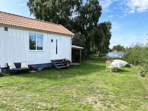 Cabaña blanca con mesa y sillas en el patio en Cozy cottage located on a nice sea plot on Boholmarna outside Kalmar en Kalmar