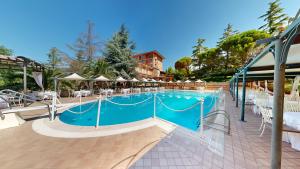 a large swimming pool with white chairs and a building at Relais La Fattoria in Melfi