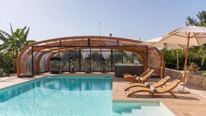 einen Pool mit 2 Stühlen und einem Sonnenschirm in der Unterkunft VILLA I MORI 4, Emma Villas in Rosolini