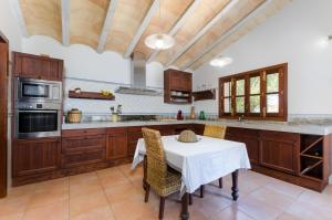 a kitchen with wooden cabinets and a white table with chairs at Es Vedat 4 in Lloret de Vistalegre