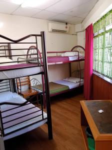 a dorm room with three bunk beds and a table at Meera Heritage Motel in George Town