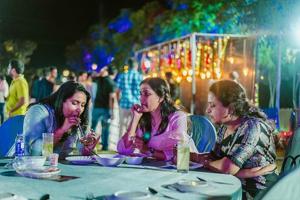 three women sitting at a table eating food at Farm Stay Resort - Shamirpet, Hyderabad in Hyderabad