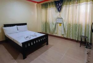 a bedroom with a bed and a window with curtains at RedDoorz @ Johsons Pension House Butuan City in Butuan