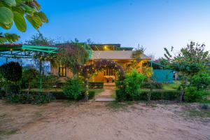een huis met een prieel ervoor bij GiriSadan Organic Farm Retreat & Botanical Forest in Jaipur