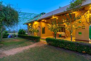 Una gran casa amarilla con un jardín enfrente. en GiriSadan Organic Farm Retreat & Botanical Forest en Jaipur