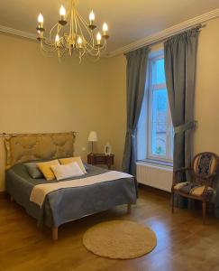 1 dormitorio con cama, lámpara de araña y ventana en Les Gîtes du Domaine de la Traxène, en Coupelle-Vieille