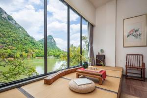 a room with a large window with a view of a river at Guilin HeShe Lakeside Resort in Guilin