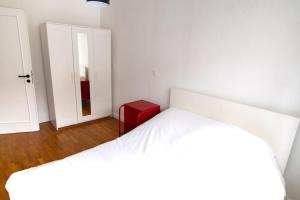 una camera bianca con un letto bianco e uno sgabello rosso di Le Gutenberg - Joli T2 dans le Carré d'Or a Strasburgo