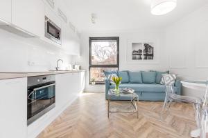 a living room with a blue couch and a kitchen at Flatbook - Old Town Deluxe Apartments Sauna & Parking in Gdańsk