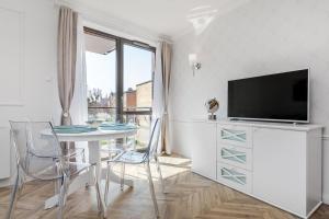 a living room with a table with chairs and a tv at Flatbook - Old Town Deluxe Apartments Sauna & Parking in Gdańsk