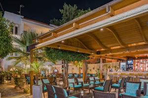 un patio con sillas y mesas y un bar en Paradise Hotel-Apartments, en Stalida