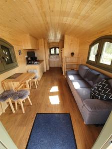 ein Wohnzimmer eines winzigen Hauses mit einem Sofa und einem Tisch in der Unterkunft Ferienpark Auf dem Simpel - Schäferwagen 4 in Soltau