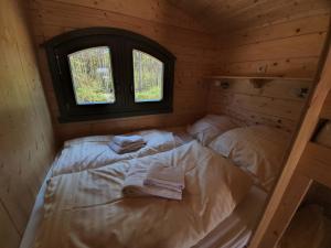 Una cama en una cabaña con dos toallas. en Ferienpark Auf dem Simpel - Schäferwagen 3, en Soltau