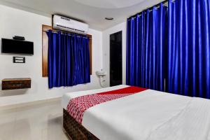 a bedroom with blue curtains and a bed and a tv at Seshadri Homestay in Tirupati