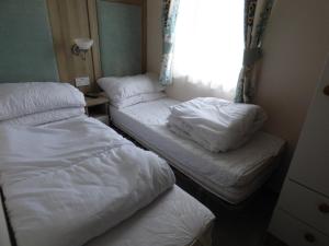two beds in a small room with a window at Meadows 49 at Southview Leisure Park in Skegness
