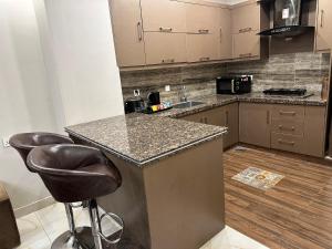 a kitchen with a counter and two bar stools at Imperial Suites in Lahore