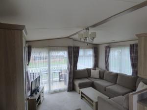 a living room with a couch and a tv at Meadows 49 at Southview Leisure Park in Skegness