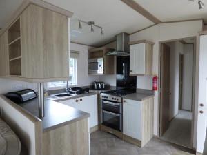 a kitchen with white cabinets and a stove top oven at Meadows 49 at Southview Leisure Park in Skegness