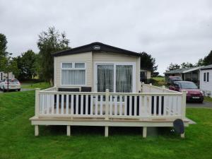 a small house with a porch on the grass at Meadows 49 at Southview Leisure Park in Skegness
