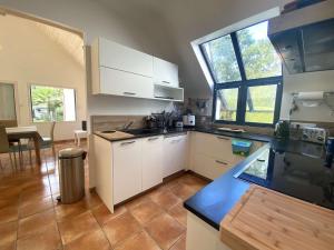 une cuisine avec des placards blancs et une grande fenêtre dans l'établissement Maison pour grande famille avec jardin, terrasse, proche Golf et Port à La Forêt-Fouesnant - FR-1-481-149, à La Forêt-Fouesnant