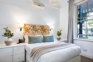 a white bedroom with a bed and a window at Welgelegen House in Cape Town