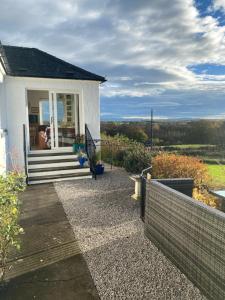 une petite maison blanche avec des escaliers et une terrasse couverte dans l'établissement Jacquie's B&B -Dumfries-Room with a view - hot tub, à Dumfries