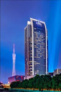 a tall building with a tower in front of it at The Ritz-Carlton, Guangzhou - Free shuttle between hotel and Exhibition Center during Canton Fair & Exhibitor registration Counter in Guangzhou