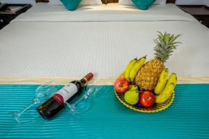 un piatto di frutta e una bottiglia di vino su un letto di Baga Fantacia Beach Inn a Calangute