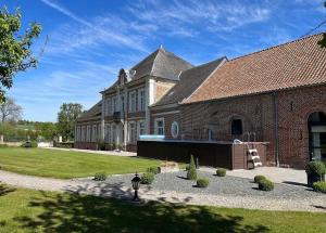 a large brick building with a pool in front of it at Les Gîtes du Domaine de la Traxène in Coupelle-Vieille