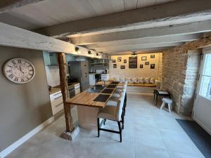 una cocina con una mesa larga y un reloj en la pared en Bergerie du Causse en Livernon