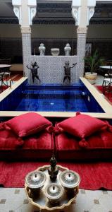 Cette chambre comprend une table avec des oreillers rouges et une piscine. dans l'établissement Riad Amazing, à Marrakech