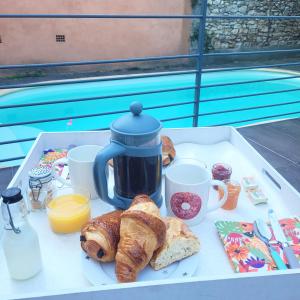 uma bandeja de comida com croissants e café numa mesa em Allegria Nimes Chambre Deluxe Spa em Nîmes