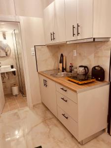 una cocina con armarios blancos y fregadero en Cactus Luxury suite2, en Atenas