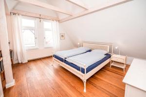 a white bedroom with a bed and a window at Haus Strandgut in Norderney