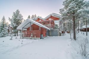 a red house in the snow with trees at Levillas Kätkänpolku Villas in Levi